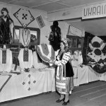 A Ukraine woman displays clothing at the "New Australian's Handicrafts" exhibition at Bathurst Migrant Camp c.1951. Courtesy National Archives of Australia