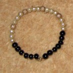 This is a [baby] bracelet somebody gifted [my son]. It is made of silver, white and black beads.