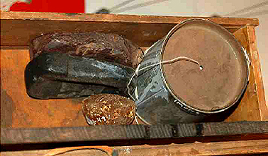 Two blocks of bees wax and one block of resin, used to wax thread. Leather stitching string in a food tin with hole in lid for release of the string, labelled 