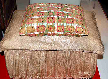 Satin covered bedroom chest adapted from a timber packing crate with decorated hessian-sack cushion.