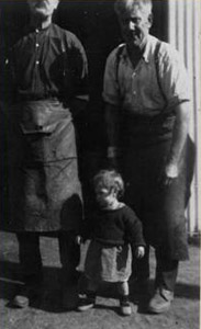 Carl Konemann on the right wearing his protective leather apron, outside the blacksmith's shop