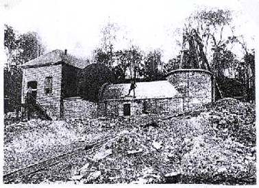 Ventilation fan house at Seaham Colliery, Hunter Valley. Engine house to left, then circular fan housing to left of the person on the roof, and air shaft and headframe to right. Inclined tramway in foreground. Courtesy NSW Mines Department Annual Report 1900.