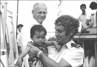 Customs Officer Frank Dalton holding a Vietnamese refugee child, Xye Than Hue on the deck of the Tu Do in Darwin, November 1977. Courtesy National Library of Australia